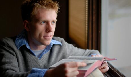 man in blue sweater reading book