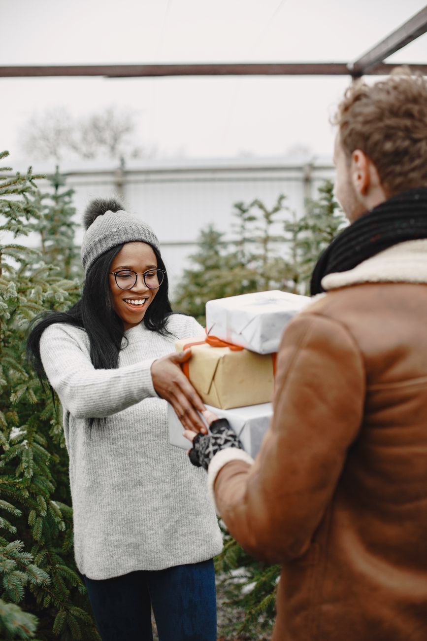 a man surprising his woman with christmas presents